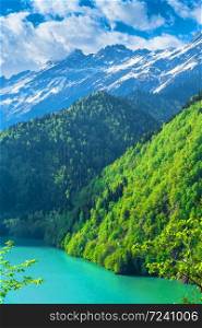 Beautiful Lake Ritsa in the Caucasus Mountains. Green mountain hills, blue sky with clouds. Spring landscape. Beautiful Lake Ritsa in the Caucasus Mountains. Green mountain hills, blue sky with clouds. Spring landscape.