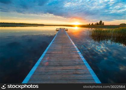 beautiful landscape - a long wooden pier and the setting sun over a picturesque lake