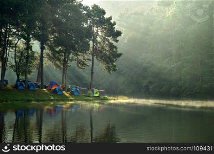 beautiful landscape, camping tents at outdoor camp site near the lake with sunlight and mist on water
