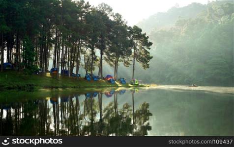 beautiful landscape, camping tents at outdoor camp site near the lake with sunlight and mist on water