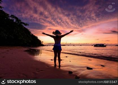 Beautiful landscape cloud and sky during sunrise while tourist woman standing outstretched arms welcoming the new day on beach at Miang island in Mu Koh Similan National Park, Phang Nga Province, Thailand