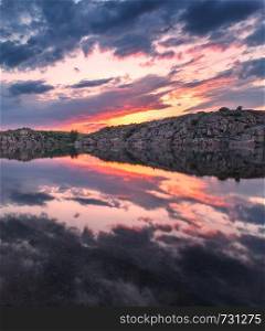 Beautiful landscape. Colorful sunset at the lake with clouds reflected in water.