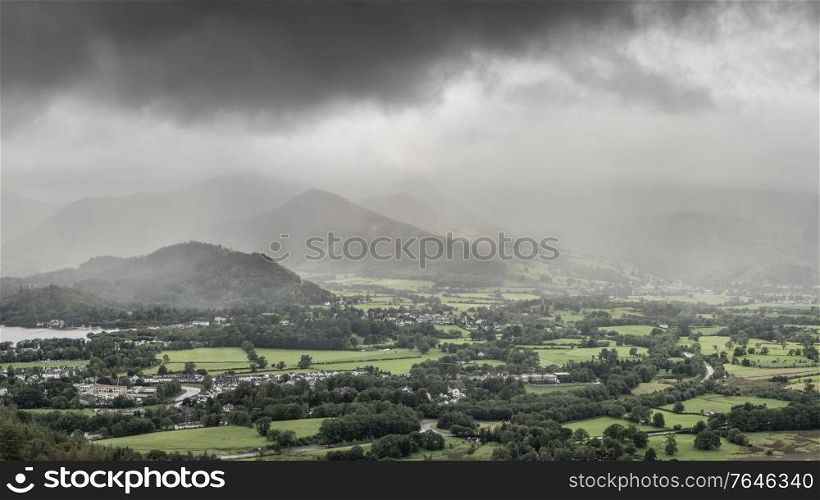 Beautiful landscape image across Derwentwater valley with falling rain drifting across the mountains onto the lush green countryside below