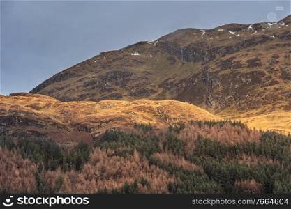 Beautiful landscape image across Loch Lomond looking towards snow capped Ben Lui mountain peak in Scottish Highlands