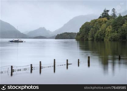 Beautiful landscape image of Derwentwater in English Lake District during late Summer morning with still water and misty mountains