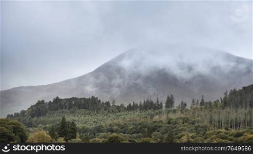Beautiful landscape image of mountain peaks in English Lake District during late Summer morning with lowcloud hanging around the mountain tops