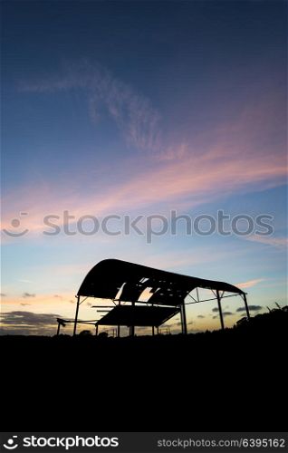 Beautiful landscape image of old derelict barn silhouette against vibrant sunset