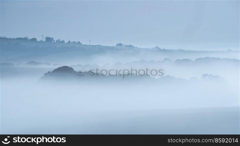 Beautiful landscape image of sea of fog rolling across South Downs English countryside during Spring sunrise