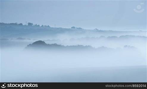 Beautiful landscape image of sea of fog rolling across South Downs English countryside during Spring sunrise
