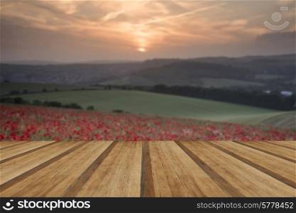 Beautiful landscape image of Summer poppy field under stunning sunset sky with wooden planks floor