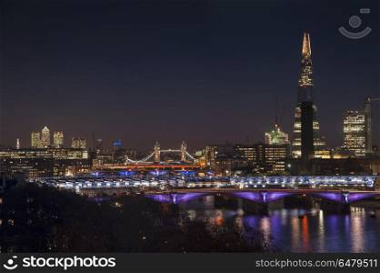 Beautiful landscape image of the London skyline at night looking. England, London, The Shard. The London skyline at night including The Shard with Tower Bridge and Canary Wharf.. Landscape image of the London skyline at night looking along the River Thames