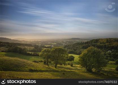 Beautiful landscape image of view over English countryside during Summer sunset with soft light providing long shadows with stunning dramatic sky