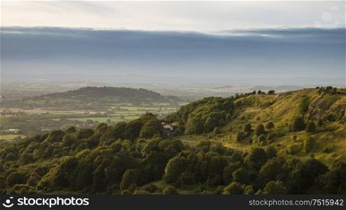 Beautiful landscape image of view over English countryside during Summer sunset with soft light providing long shadows with stunning dramatic sky