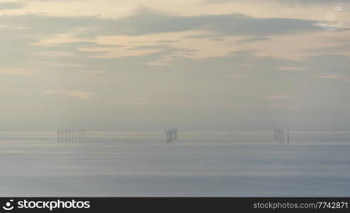 Beautiful landscape image of wind turbine farm off North coast of Wales with lovely pastel sunset colours