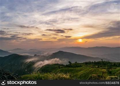 Beautiful landscape nature on mountain with sun cloud fog and bright colors of sky and sunlight during sunset in winter at view point Phu Chi Fa Forest Park in Chiang Rai Province, Thailand