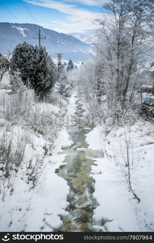 Beautiful landscape of fast mountain stream at forest covered by snow