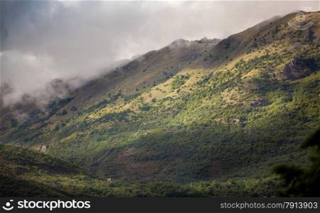 Beautiful landscape of high mountains grown with grass covered with clouds