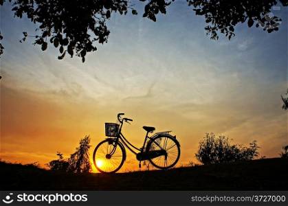 Beautiful landscape of nature with impression of the sun and silhouette of bicycle in sunrise at countryside
