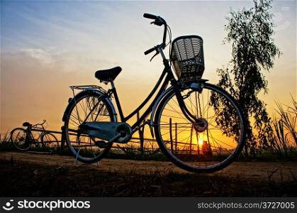 Beautiful landscape of nature with impression &rsquo;s sun and silhouette of two bicycles in sunrise at countryside