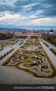 Beautiful landscape of palace complex Schloss Belvedere and garden parterre with regular planting of plants and flowers in Vienna, Austria on a background of cloudy sky.. Palace complex Schloss Belvedere with parterre garden in Vienna.