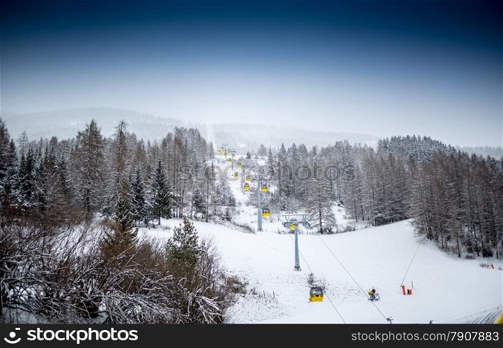 Beautiful landscape of ski lift on slope at mountain covered by pines