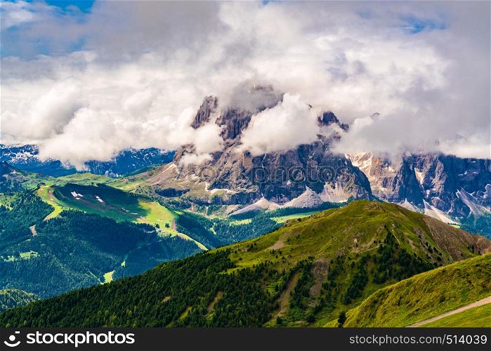 Beautiful landscape of the Limestone mountain the Dolomites in sunny day with the the clouds on the top and a small village at the valley seen from the Secada Peak in South Tyrol Italy