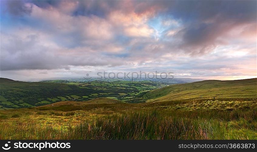 Beautiful landscape panorama across countryside to mountains in distance with moody sky