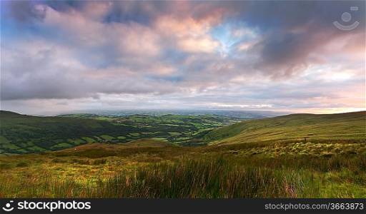 Beautiful landscape panorama across countryside to mountains in distance with moody sky