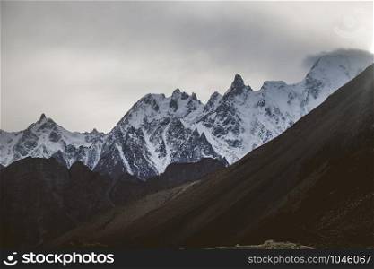 Beautiful landscape scenery of sunset at Passu in the dusk. Snow capped massif mountain peaks in Karakoram range with fog and clouds, Gojal Hunza. Gilgit Baltistan, Pakistan.