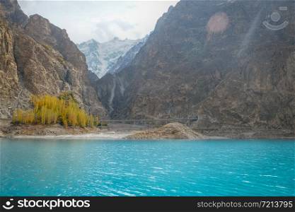 Beautiful landscape scenery of turquoise blue water of Attabad lake in autumn season against snow capped mountain in Karakoram range. Gojal, Hunza Valley. Gilgit Baltistan, Pakistan.