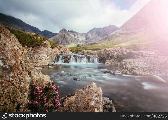 Beautiful landscape scenery with waterfalls in the mountains: The Fairy Pools, Isle of Skye, Scotland. Sunshine.