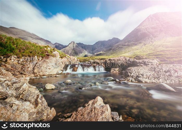 Beautiful landscape scenery with waterfalls in the mountains: The Fairy Pools, Isle of Skye, Scotland. Sunshine.