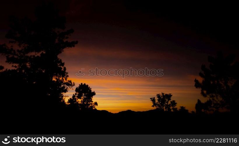 Beautiful landscape silhouette on the mountain peak during sunset with warm sunlight and dramatic sky.