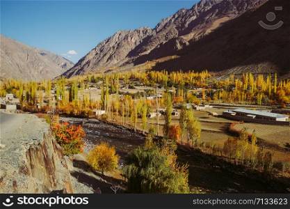 Beautiful landscape view of small village in Gupis valley in the morning against Hindu Kush mountain range. Colorful trees in autumn season in Gilgit Baltistan, Pakistan.