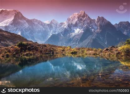 Beautiful landscape with high mountains with snow covered peaks, sky reflected in lake. Mountain valley with reflection in water in sunrise. Nepal. Amazing scene with Himalayan mountains. Nature. Mountain valley with reflection in water in sunrise