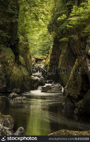 Beautiful landscape with river flowing through deep sided gorge with vibrant green foliage