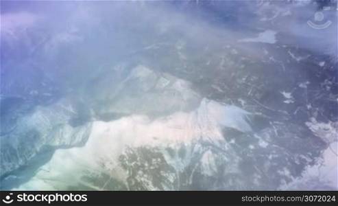 Beautiful landscape with rocky snowy mountains and canyon. Beauty of nature which can be seen from the airplane through the thin clouds
