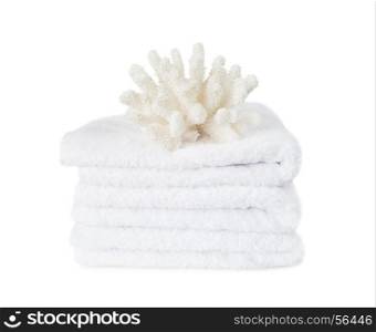 Beautiful large white coral on the stack of white fluffy terry towels isolated on a white background. white coral on the white terry towels