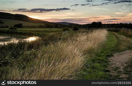 Beautiful late Summer sunset over river in countryside landscape