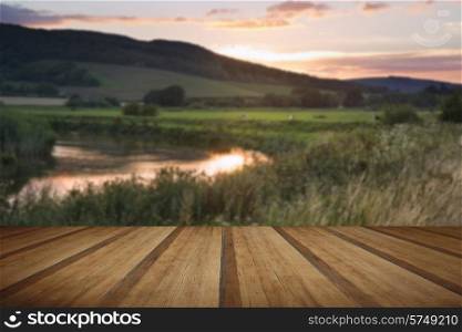 Beautiful late Summer sunset over river in countryside landscape with wooden planks floor
