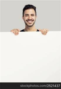 Beautiful latin man smiling and holding a blank billboard