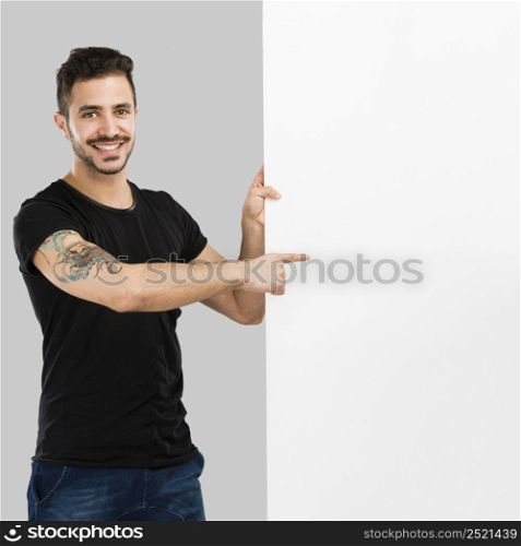 Beautiful latin man smiling and pointing to a blank billboard