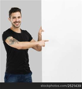 Beautiful latin man smiling and pointing to a blank billboard