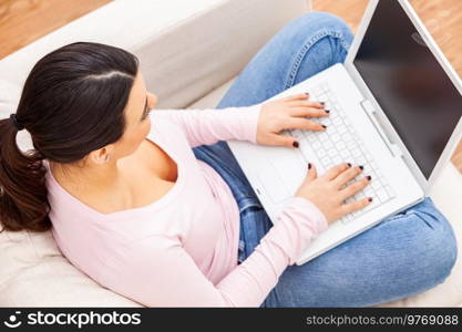 Beautiful  Latina Hispanic girl female young woman using a laptop computer for on line shopping or social media at home on her sofa