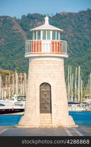beautiful lighthouse on the background of mountains and moored yachts