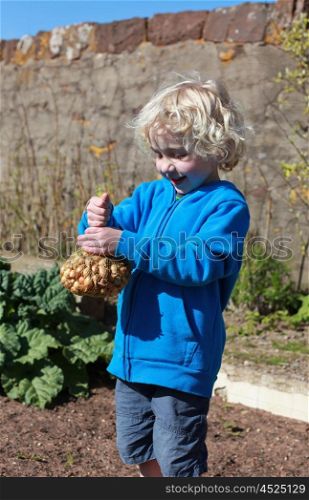 Beautiful little boy holding a net of onions ready to plant