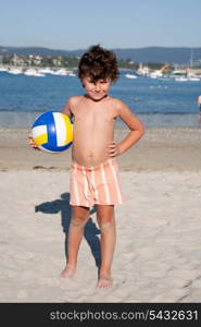 Beautiful little boy on the beach with a soccer ball