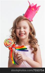 Beautiful little candy princess girl in crown holding big lollipop and laughing. Girl in crown holding lollipop