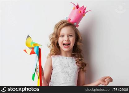 Beautiful little candy princess girl in crown holding pinwheel and smiling. Candy princess girl with pinwheel