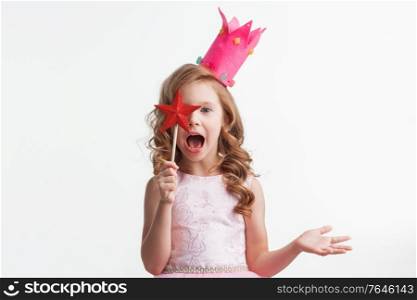 Beautiful little candy princess girl in crown holding star shaped magic wand putting spell isolated on white. Princess girl holding magic wand
